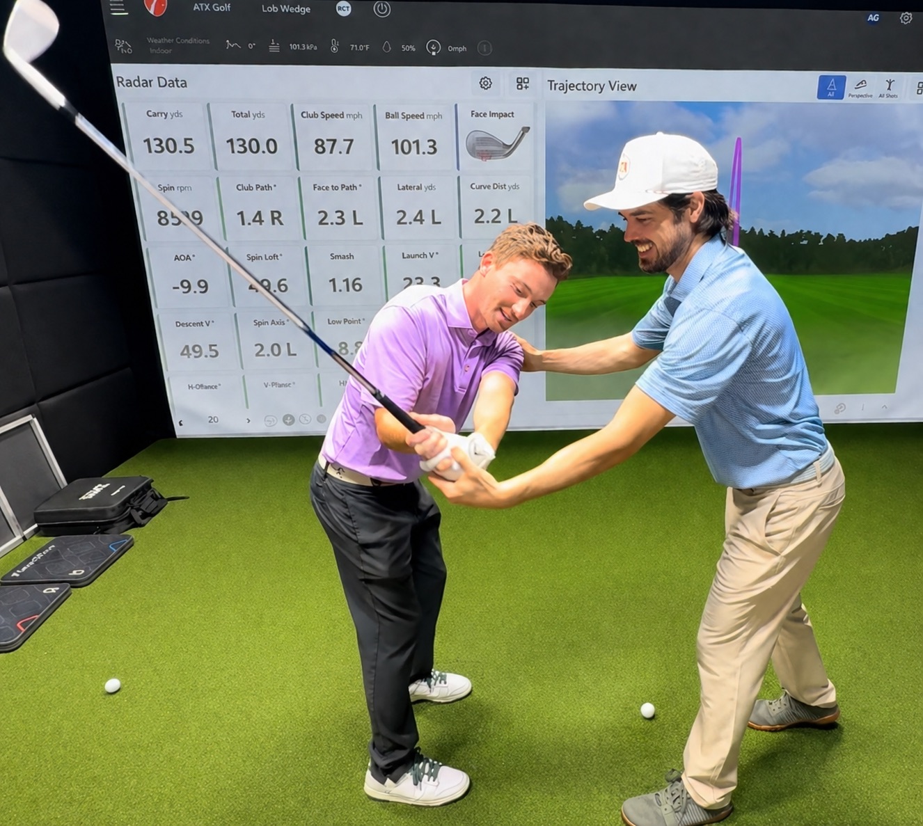 Coach Benjah coaching a student in the golf simulator bay, reviewing swing data